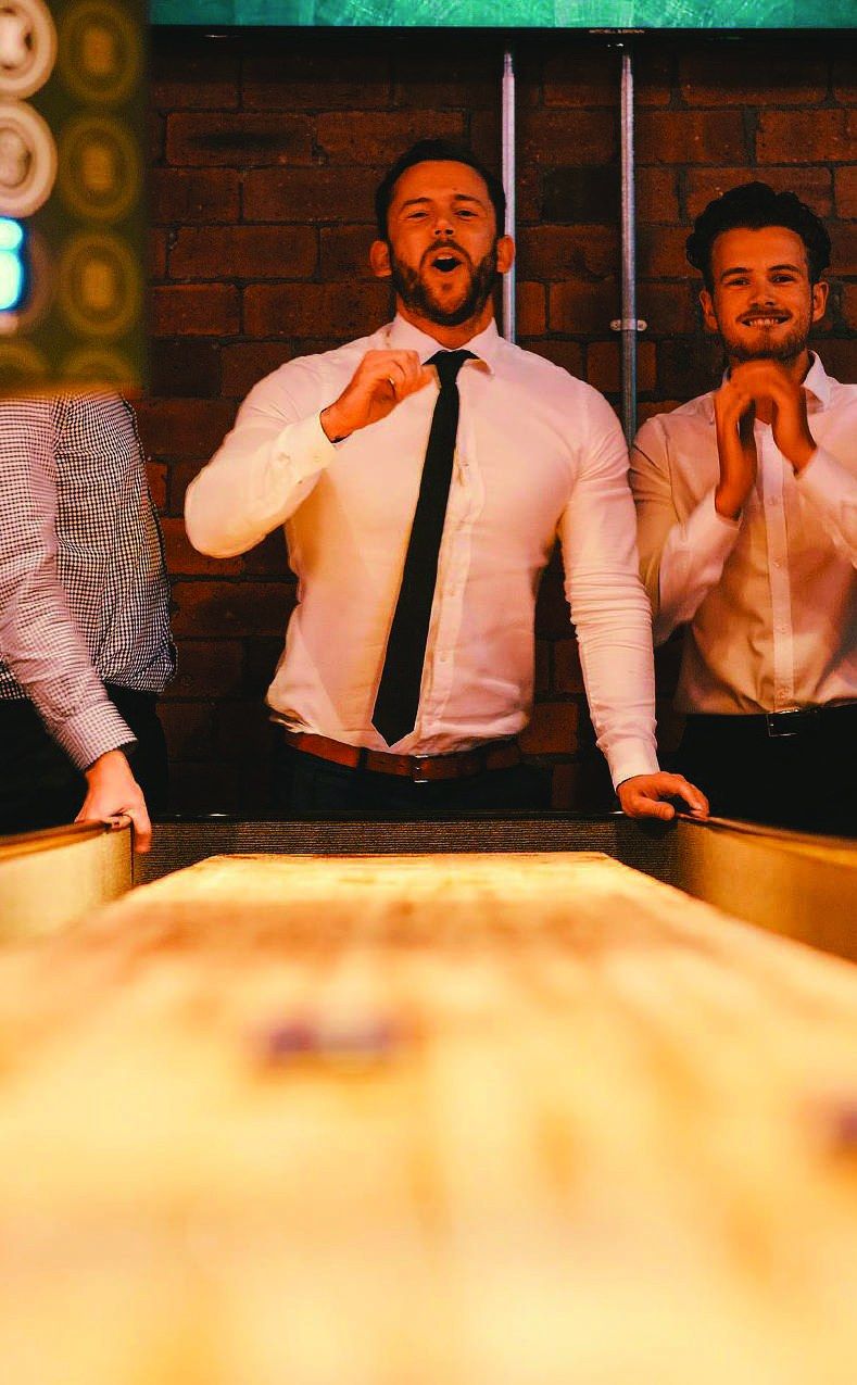 Colleagues celebrating a shuffleboard shot at a corporate event