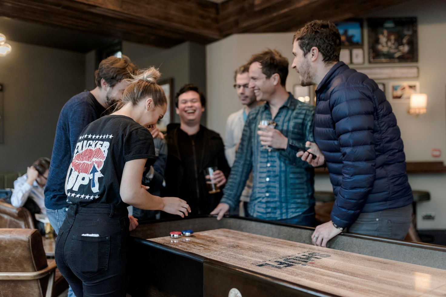 Team laughing around a shuffleboard table